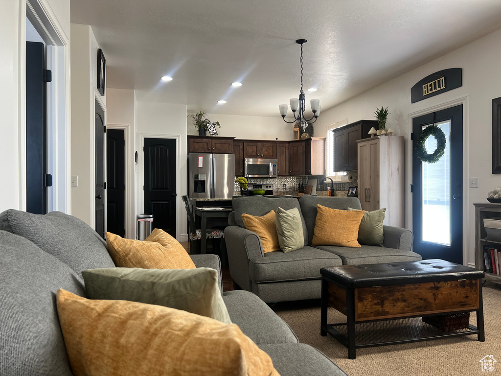 Living area featuring light colored carpet, a chandelier, and recessed lighting