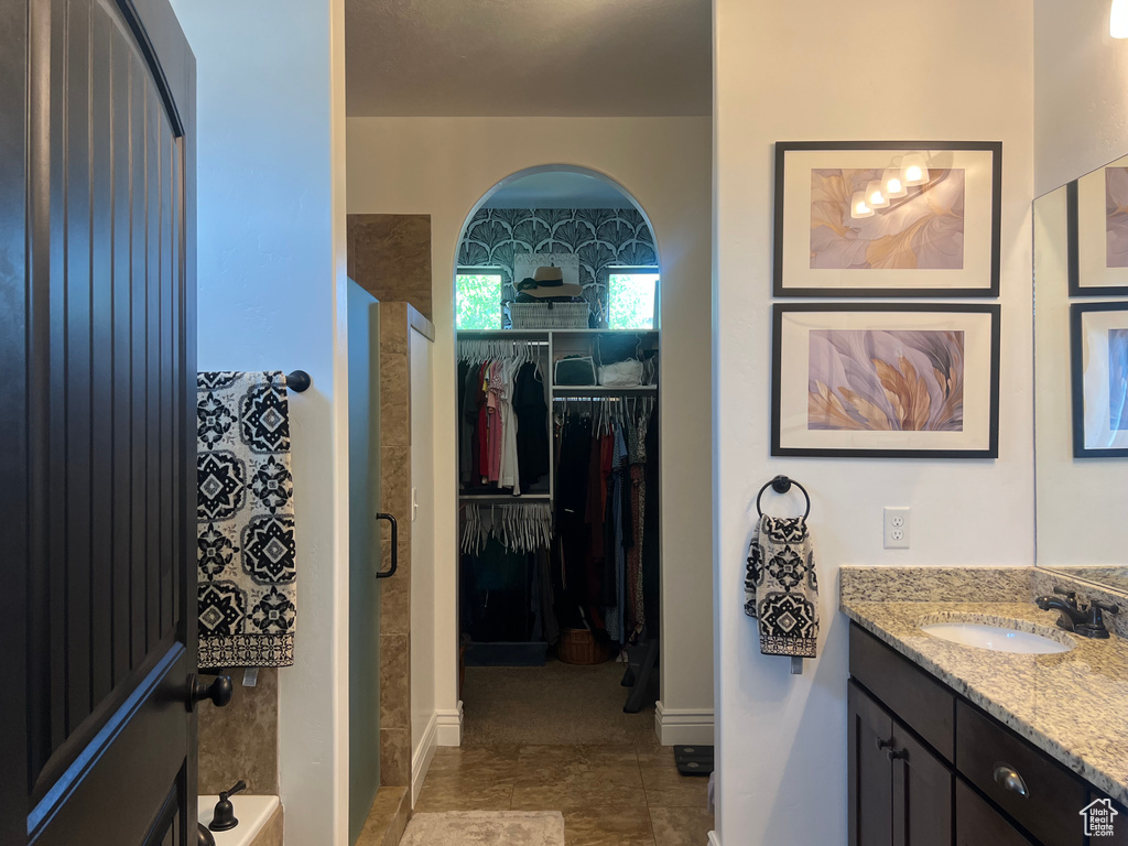Bathroom featuring a stall shower, vanity, and a walk in closet