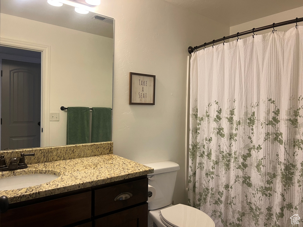 Bathroom featuring vanity, toilet, and a shower with curtain