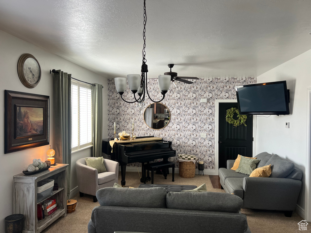 Carpeted living area featuring a chandelier, baseboards, and ceiling fan