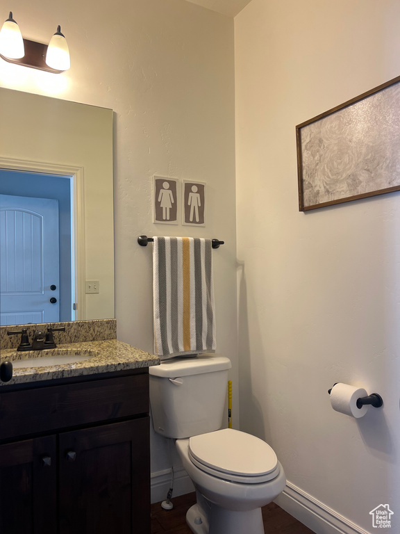 Half bathroom with toilet, vanity, and baseboards