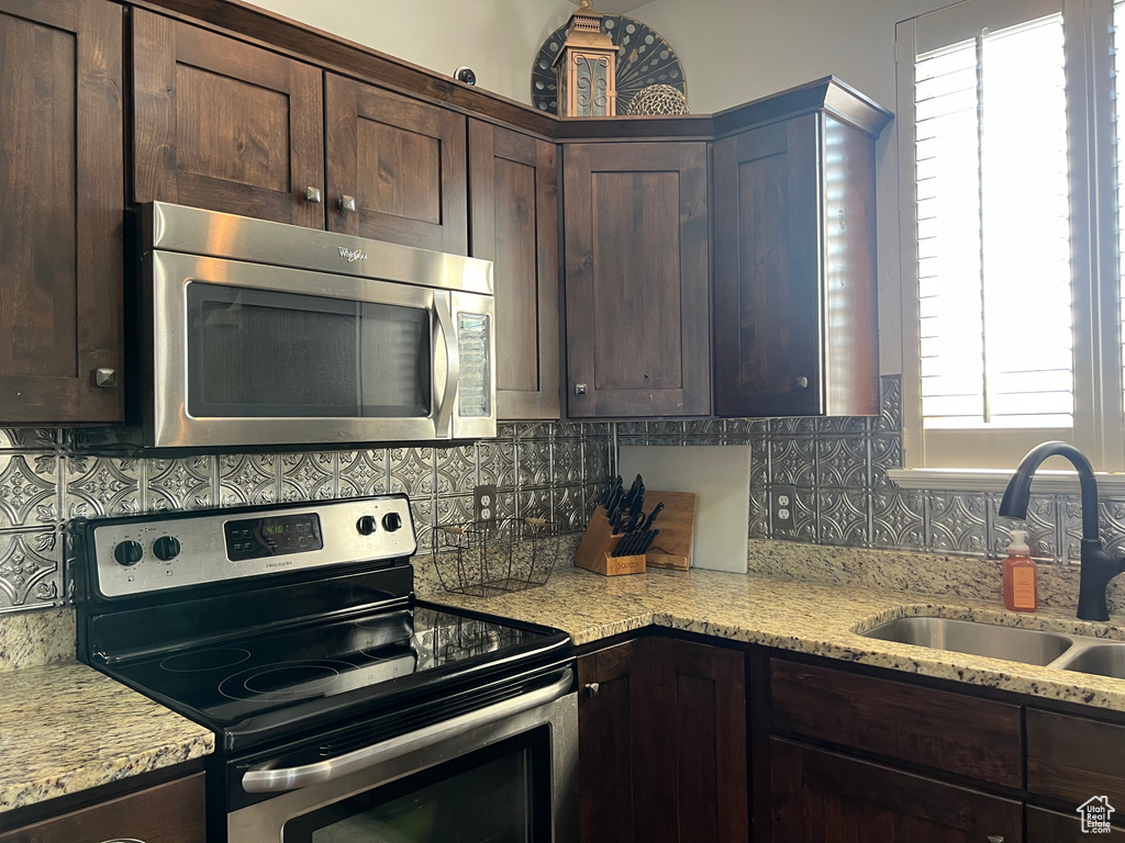 Kitchen featuring stainless steel appliances, a sink, dark brown cabinetry, and decorative backsplash