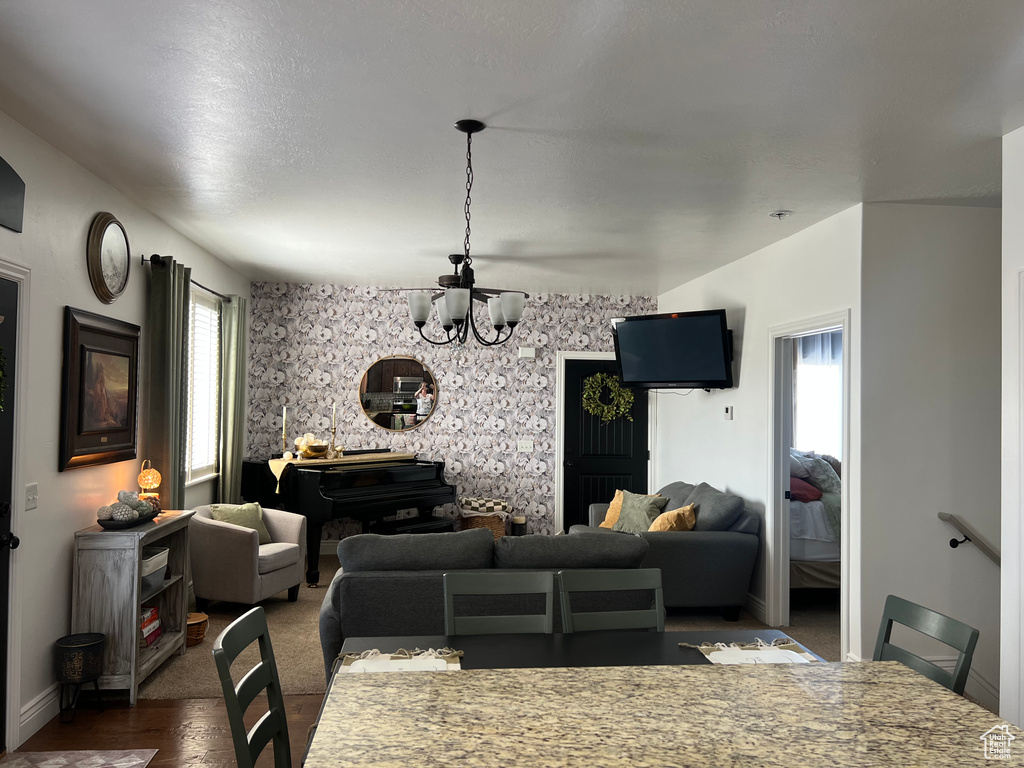 Dining area featuring a chandelier, wallpapered walls, baseboards, dark wood-style flooring, and an accent wall