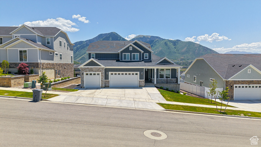 View of front of property with driveway, a mountain view, a garage, and stone siding