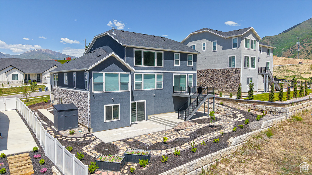 Rear view of house featuring stairs, a fenced backyard, a patio, stucco siding, and a mountain view