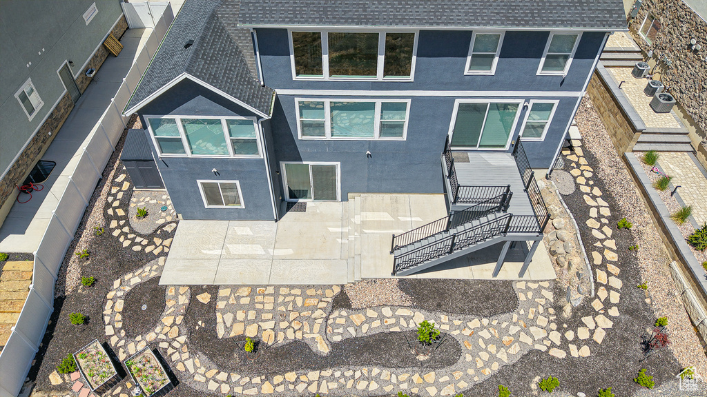 Rear view of property with stairs, stucco siding, roof with shingles, and a fenced backyard