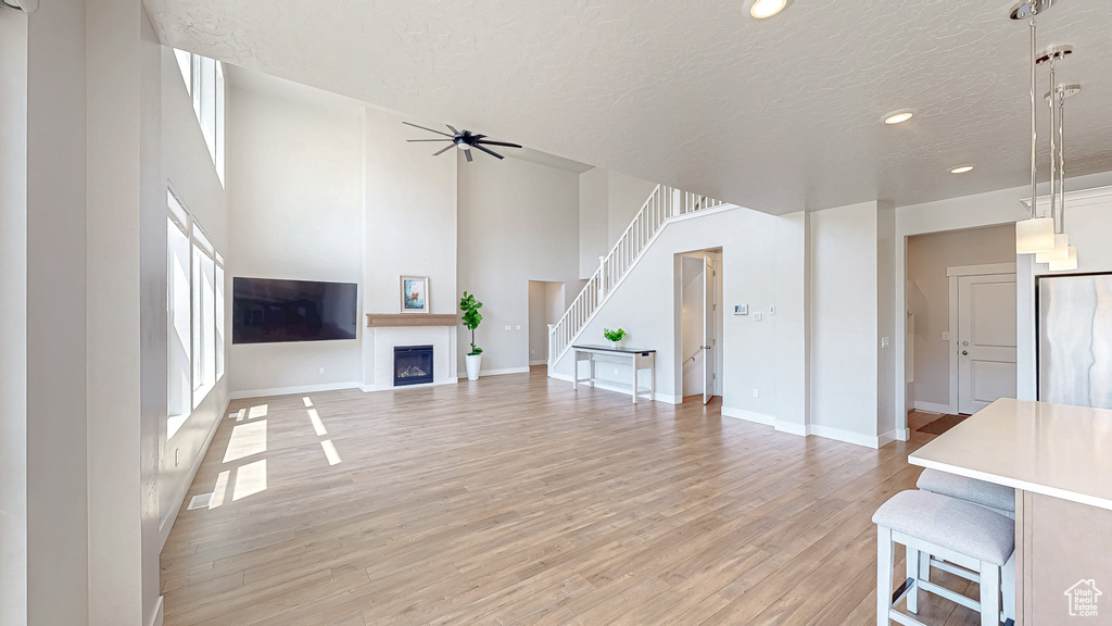 Living area with a textured ceiling, light wood-style floors, a ceiling fan, recessed lighting, and baseboards