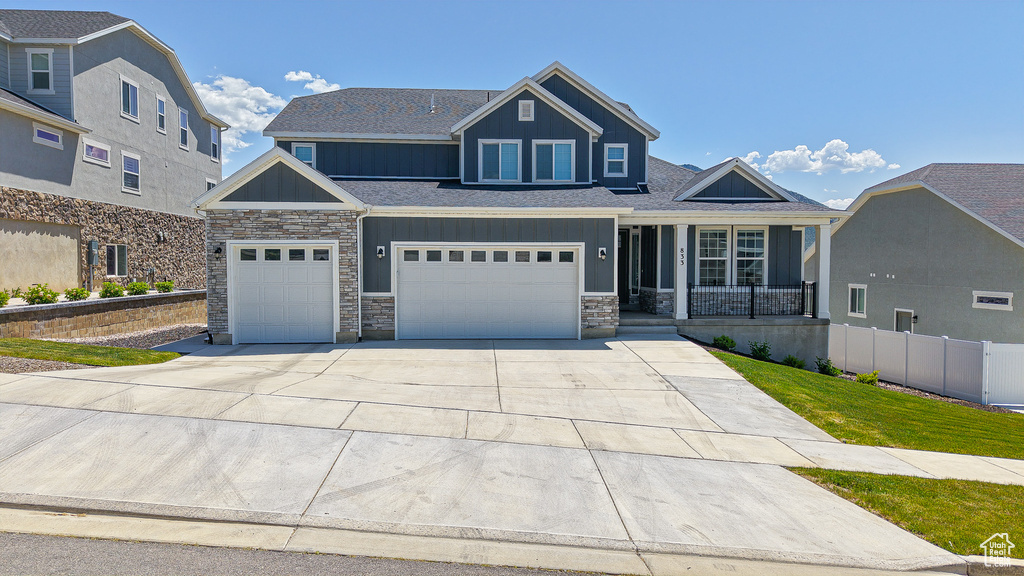 Craftsman inspired home with board and batten siding, stone siding, covered porch, and concrete driveway