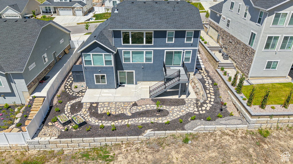 Rear view of property featuring stucco siding, a residential view, roof with shingles, a fenced backyard, and stairway