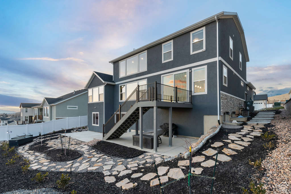 Back of property with stucco siding, a patio, stairs, and a deck