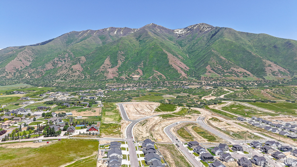 Aerial view of property and surrounding area featuring mountains and nearby suburban area