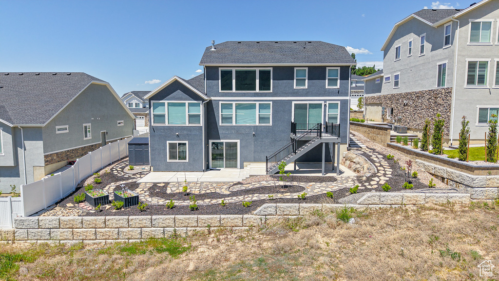 Back of house featuring stairs, a patio, a fenced backyard, stucco siding, and a residential view