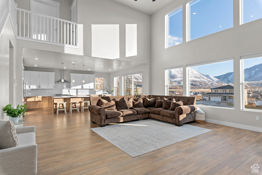 Living room featuring a mountain view, light wood-style floors, high vaulted ceiling, and baseboards