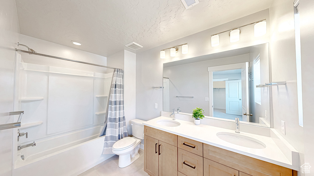 Bathroom featuring shower / tub combo, double vanity, toilet, tile patterned flooring, and a textured ceiling
