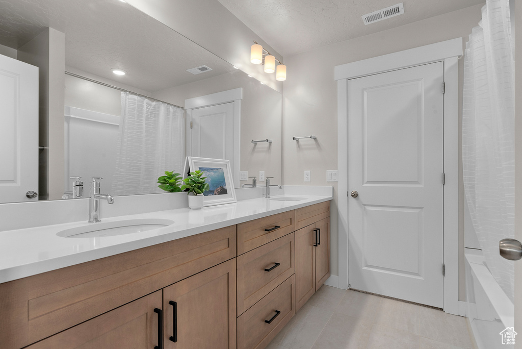 Full bathroom with double vanity, baseboards, and recessed lighting