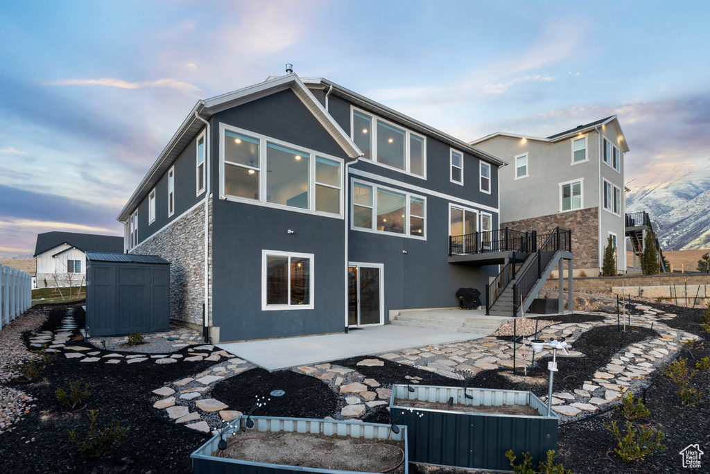 Rear view of property with stairway, a patio area, stucco siding, and stone siding