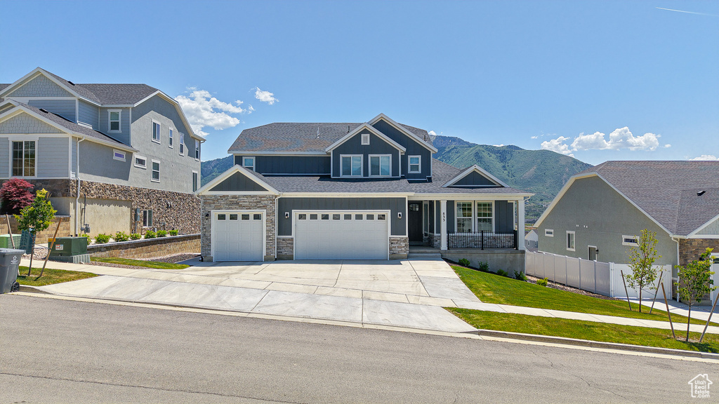 View of front facade with driveway, stone siding, board and batten siding, a mountain view, and an attached garage