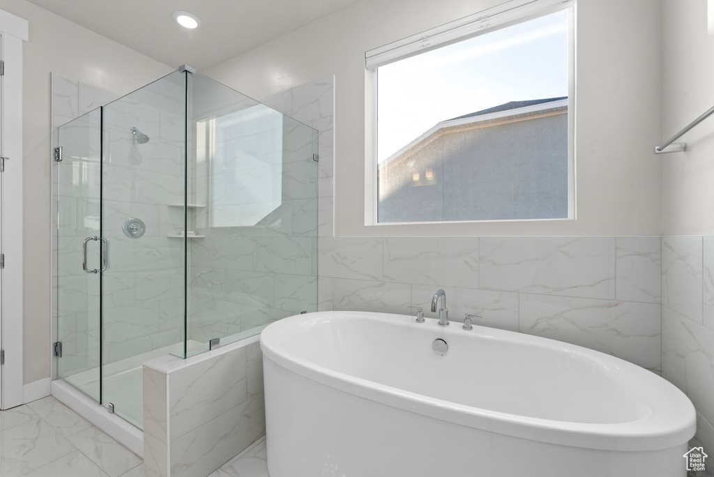 Bathroom with marble finish flooring, a marble finish shower, a freestanding bath, tile walls, and recessed lighting