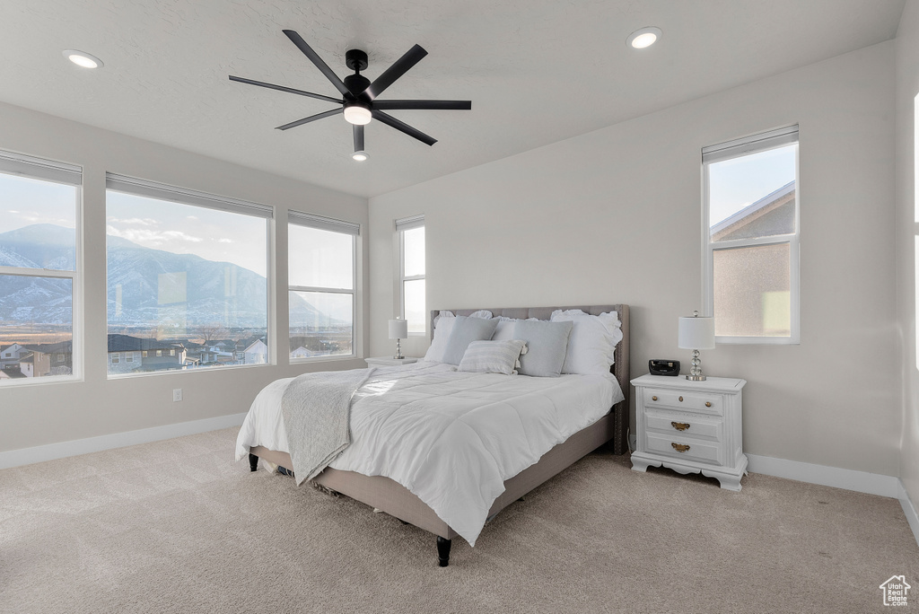 Bedroom with light colored carpet, multiple windows, baseboards, recessed lighting, and a mountain view