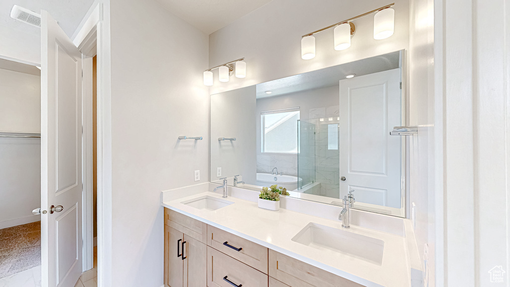 Full bath featuring a shower stall, double vanity, a garden tub, baseboards, and a spacious closet