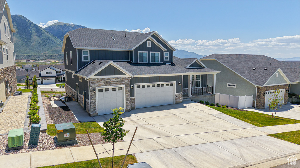 Craftsman-style house featuring board and batten siding, stone siding, roof with shingles, and driveway