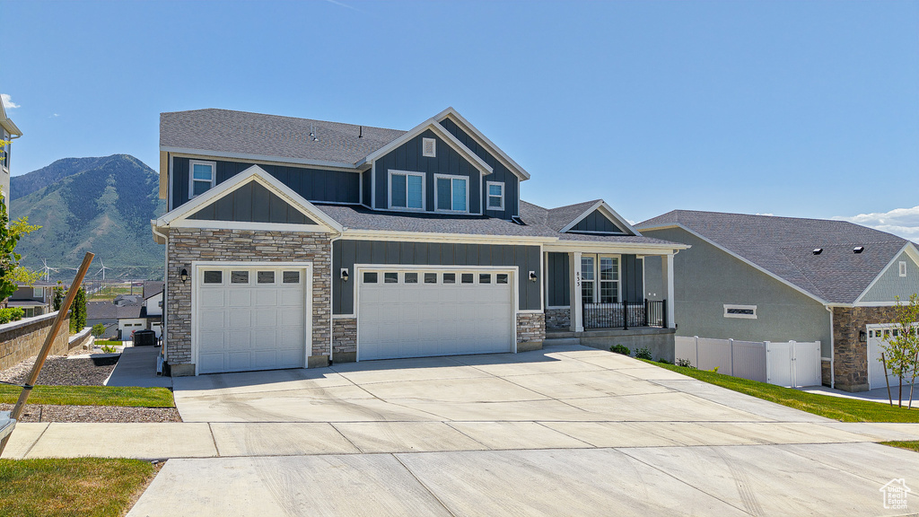 Craftsman-style home featuring board and batten siding, stone siding, concrete driveway, an attached garage, and a shingled roof