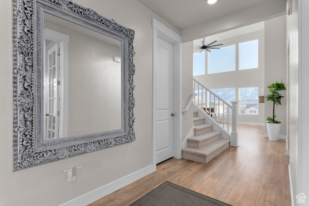Hall with baseboards, wood finished floors, stairway, and recessed lighting