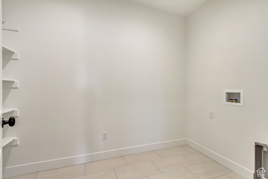 Laundry area featuring washer hookup, baseboards, and light tile patterned floors