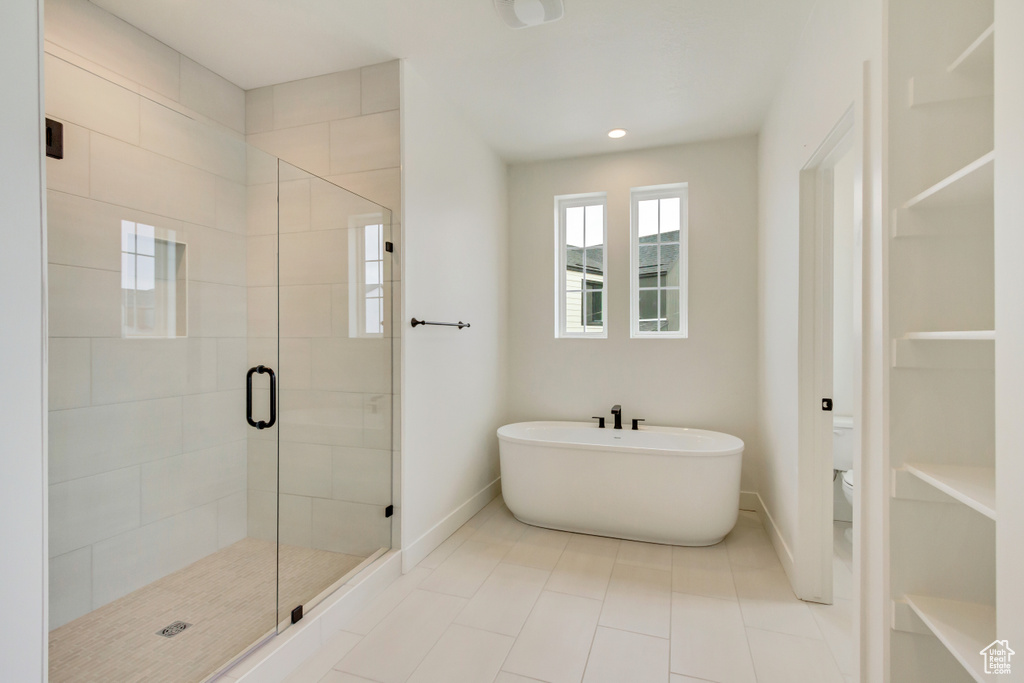 Bathroom with baseboards, a soaking tub, a shower stall, toilet, and tile patterned floors