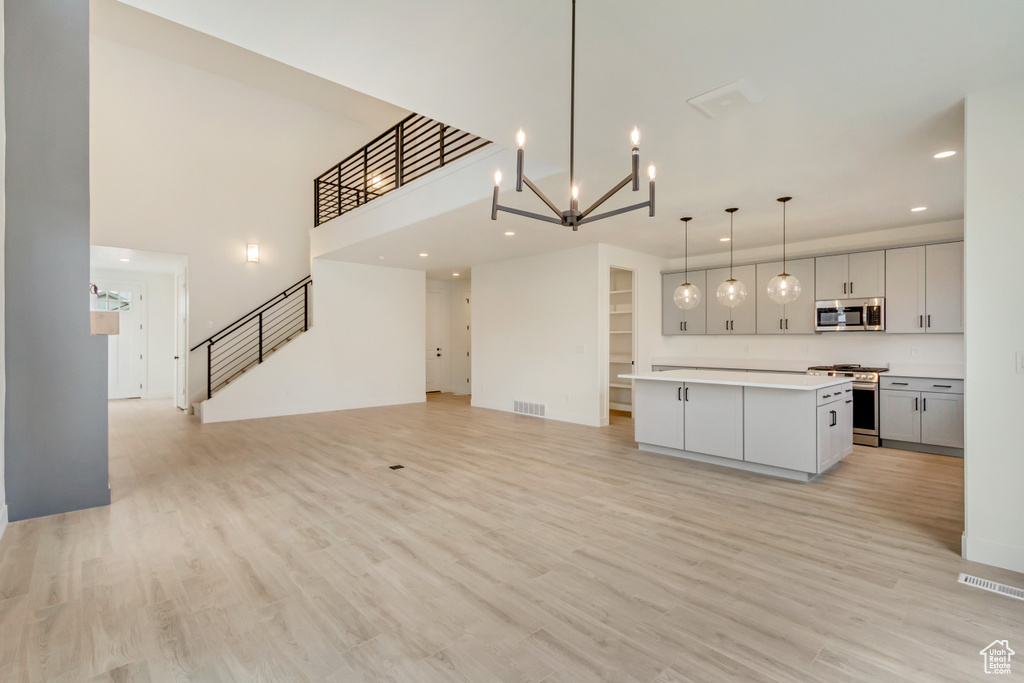 Kitchen featuring appliances with stainless steel finishes, open floor plan, light countertops, a center island, and recessed lighting