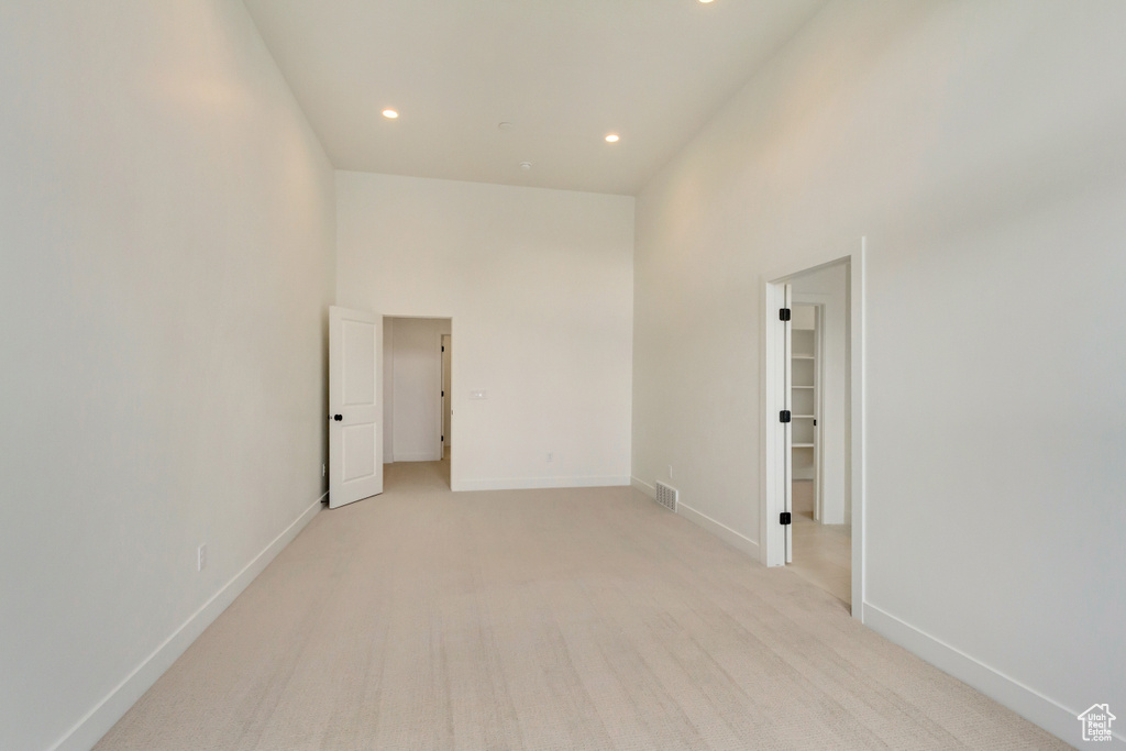 Spare room with recessed lighting, light colored carpet, a towering ceiling, and baseboards