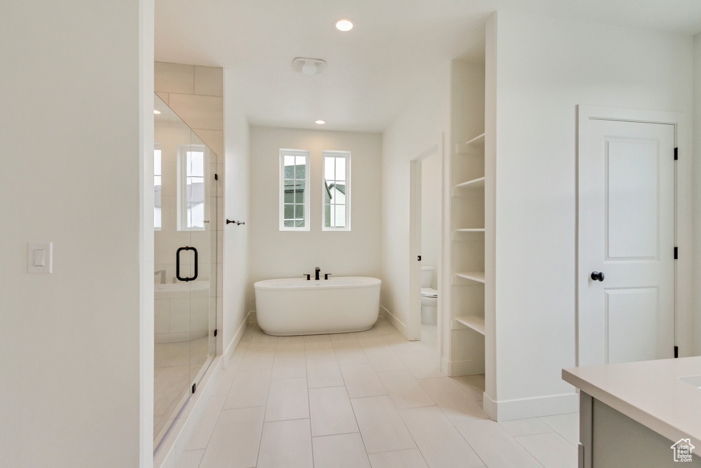 Bathroom featuring a freestanding bath, toilet, a shower stall, vanity, and baseboards