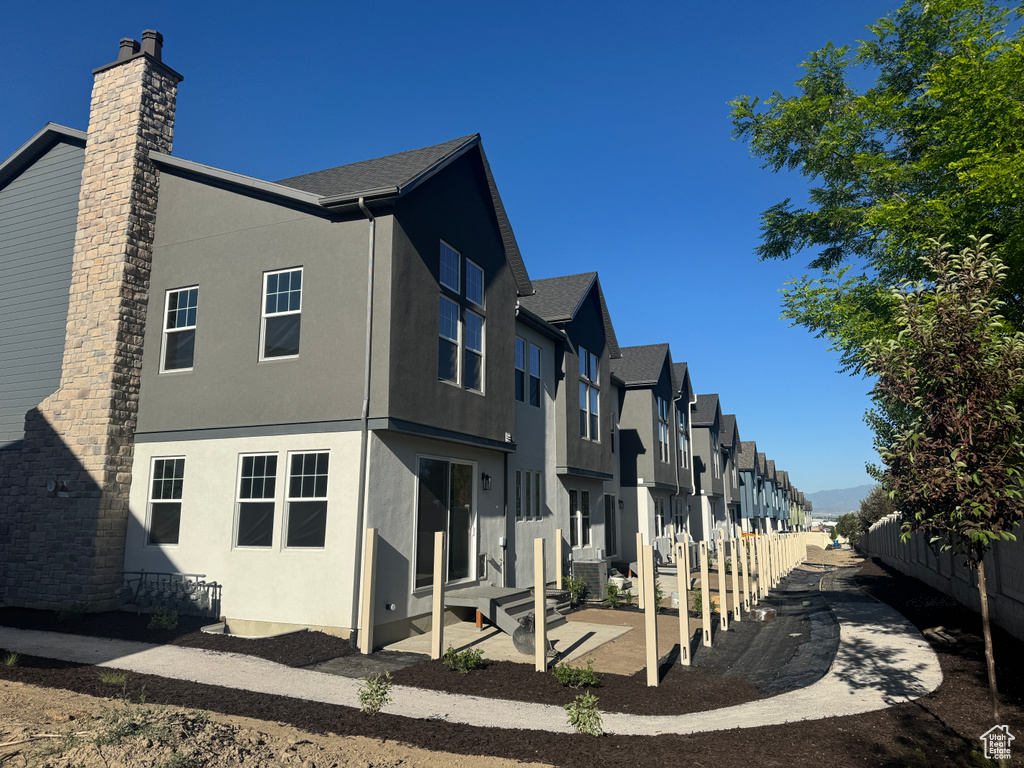 View of side of home featuring stucco siding, a residential view, and a chimney