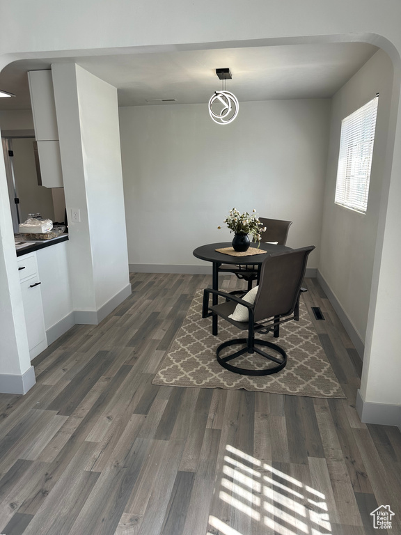 Dining space with wood finished floors, arched walkways, and baseboards