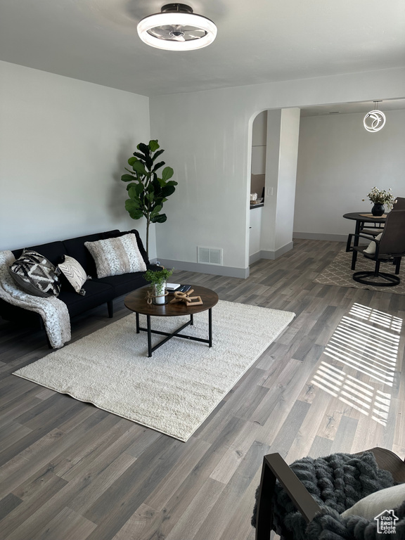 Living area with arched walkways, wood finished floors, and baseboards