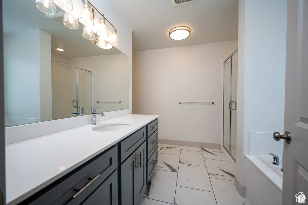 Bathroom with vanity, a stall shower, marble look tiles, and a bath