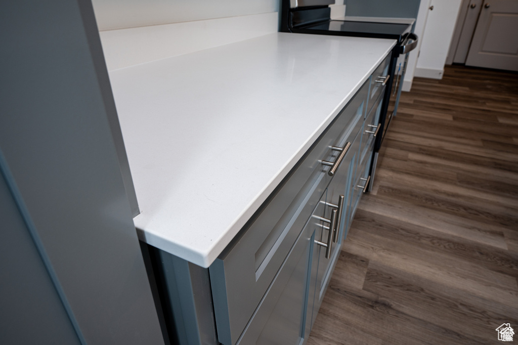 Kitchen view of dark wood-style floors, light countertops, and gray cabinets