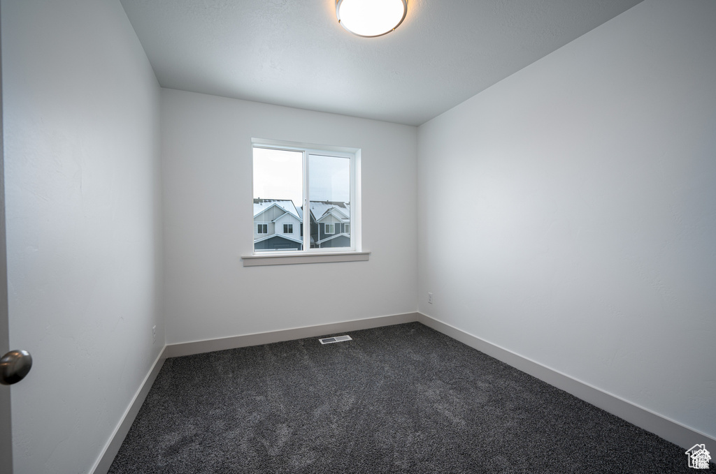 Unfurnished room with dark carpet and baseboards