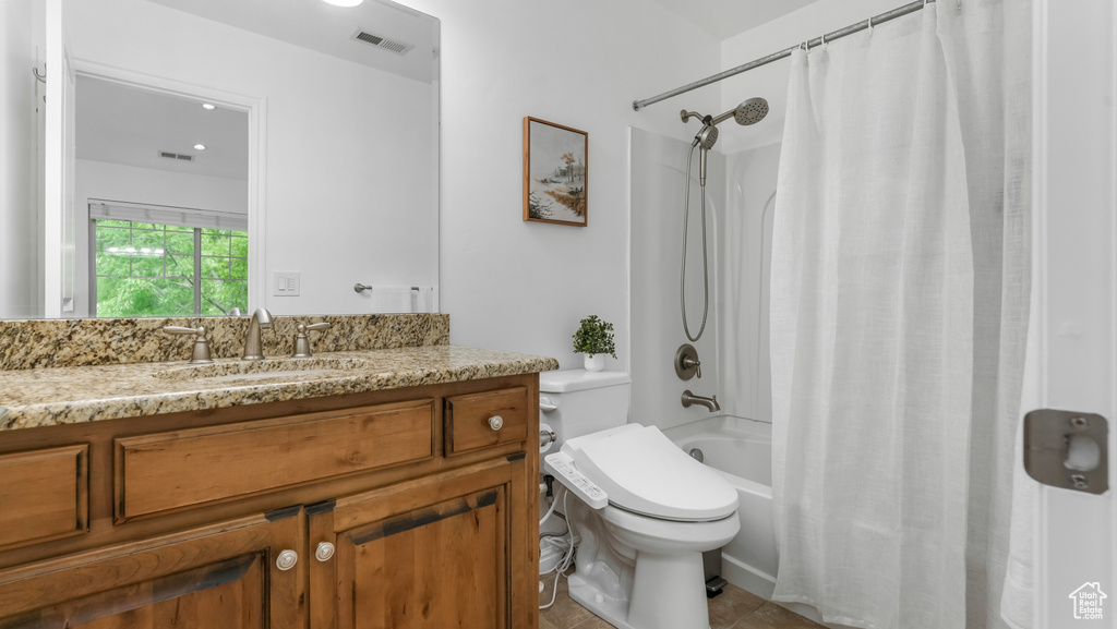 Bathroom featuring shower / bath combination with curtain, vanity, toilet, and tile patterned floors