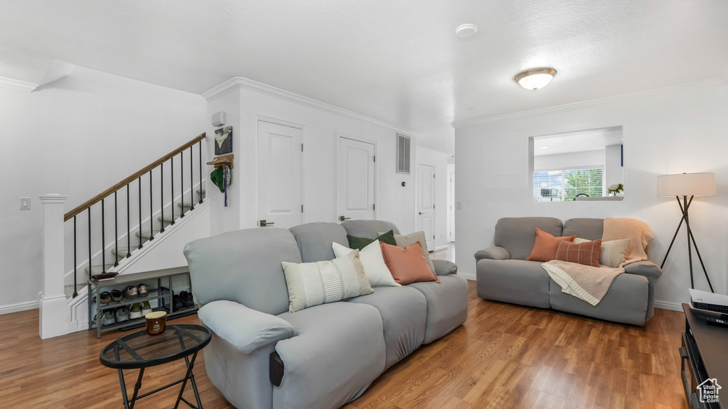Living room featuring stairs, wood finished floors, ornamental molding, and baseboards