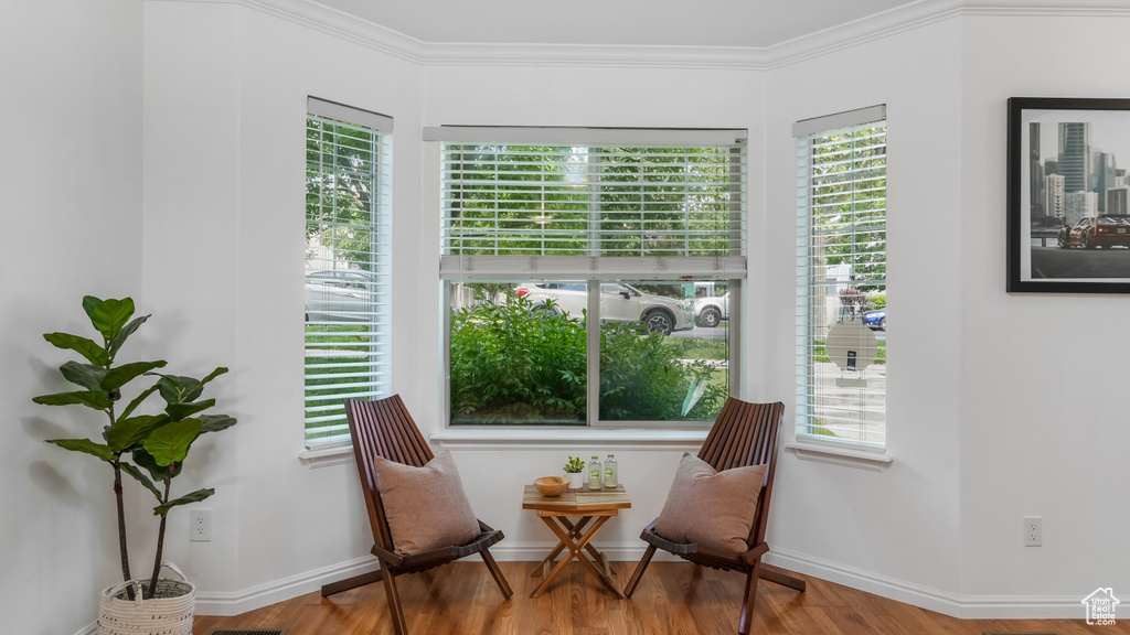Living area with healthy amount of natural light, wood finished floors, crown molding, and baseboards