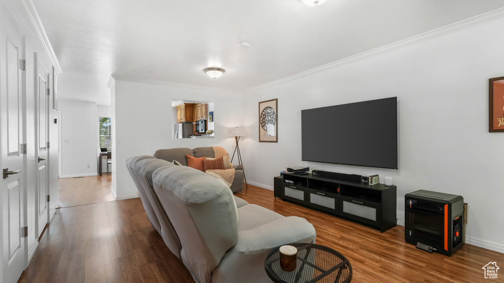 Living area with crown molding, wood finished floors, and baseboards