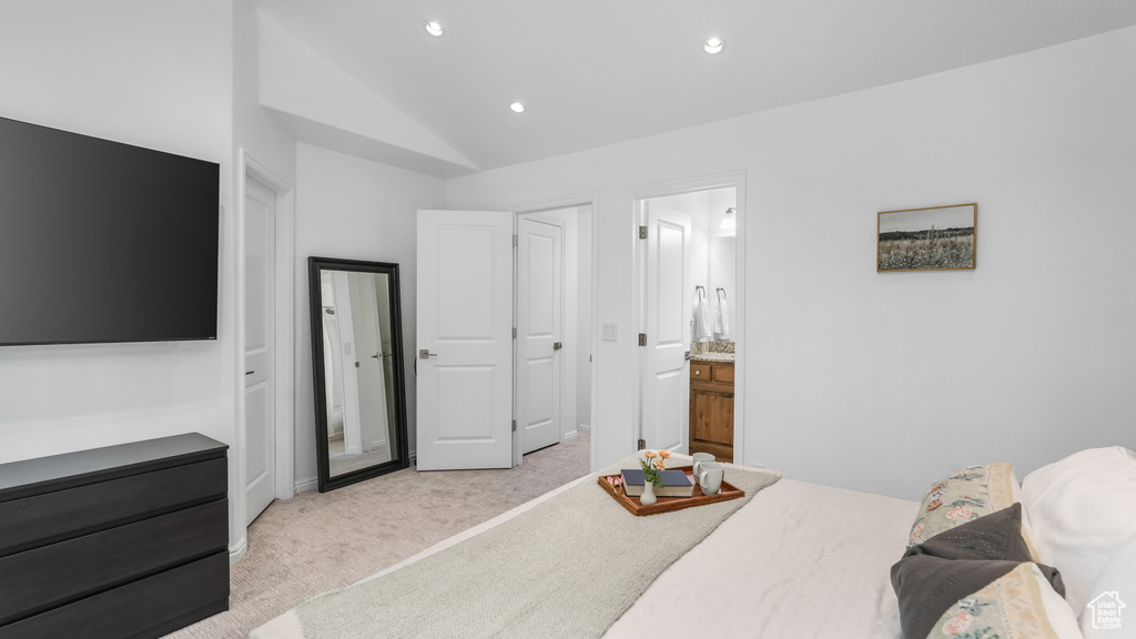 Bedroom with light colored carpet, vaulted ceiling, recessed lighting, and connected bathroom