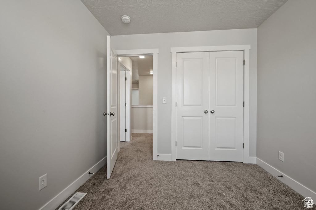 Unfurnished bedroom featuring carpet, a closet, and baseboards