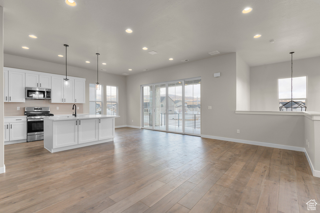 Kitchen featuring stainless steel appliances, open floor plan, baseboards, light countertops, and recessed lighting