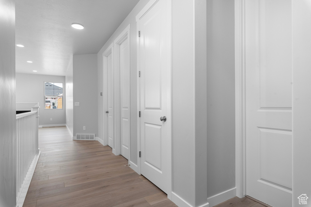 Hall with baseboards, light wood-style floors, and recessed lighting
