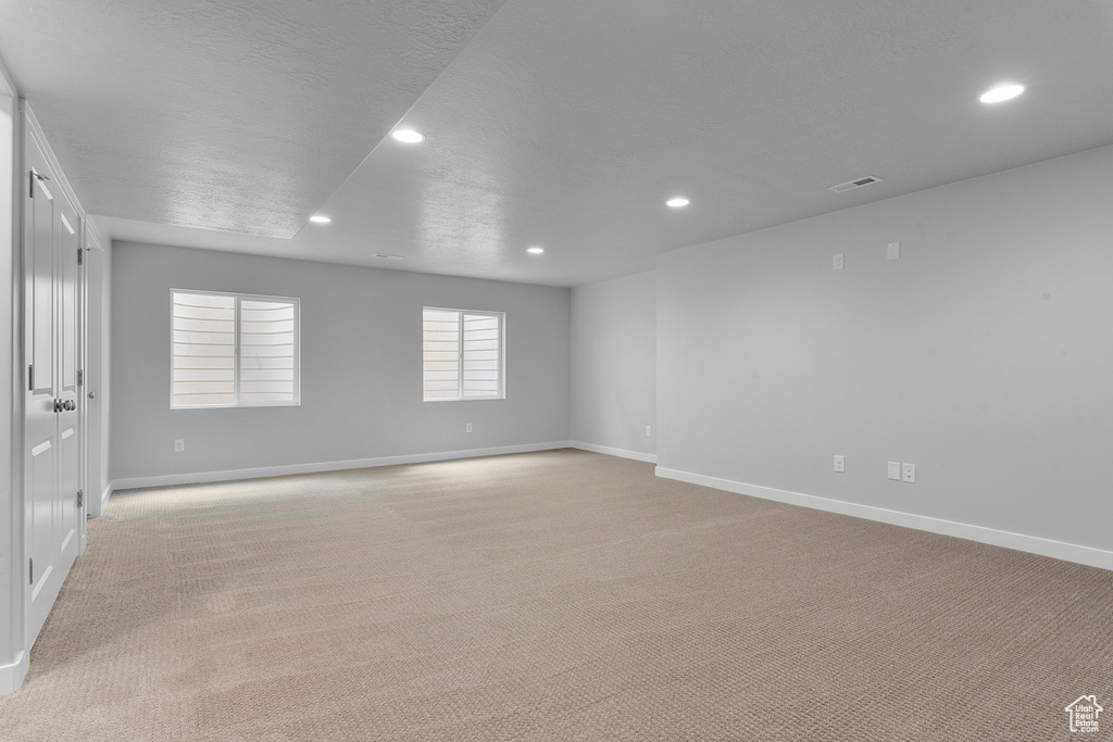 Spare room featuring recessed lighting, light carpet, and baseboards
