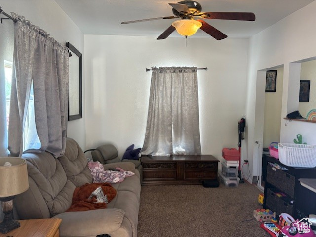 Carpeted living area featuring a ceiling fan