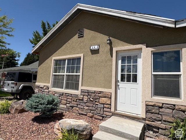 View of exterior entry featuring stone siding and stucco siding