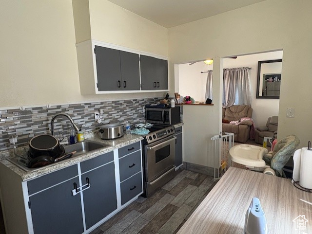 Kitchen featuring stainless steel appliances, a sink, decorative backsplash, dark wood-type flooring, and open floor plan